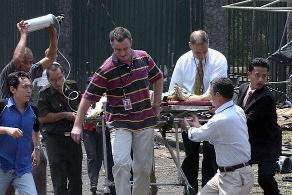 Grant Dooley (centre) helps carry embassy gardener Suryadi to an ambulance.