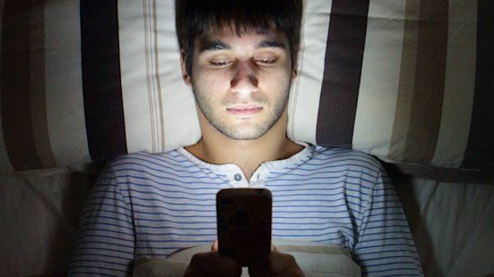Man on phone in bed. 