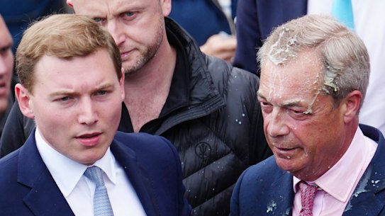 George Cottrell, wearing a blue tie, was with Farage when a woman threw a milk shake at him as he campaigned in 2024.