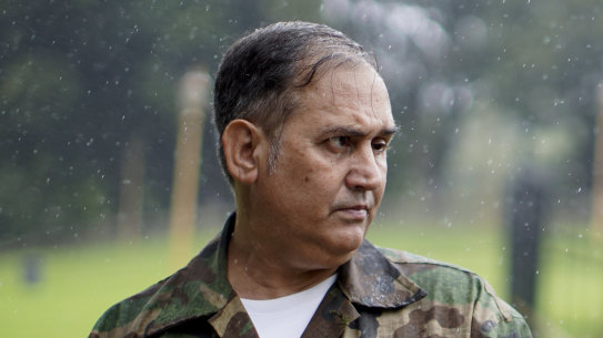 Argentine war veteran Jorge Altieri poses for a portrait with the blood-stained helmet that saved his life in 1982.