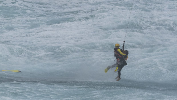 The third surf lifesaver is winched from the water near Port Campbell on Sunday.