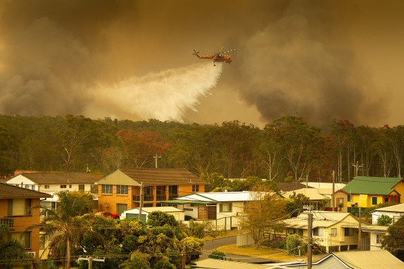 An Aircrane water bombing helicopter drops water on a bushfires in Harrington, 335 kilometres north-east of Sydney.
