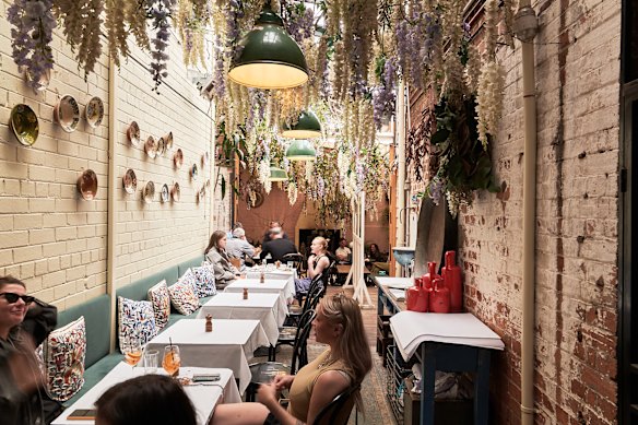 The bright sunroom is the spot to sit, beneath sweeping wisteria.