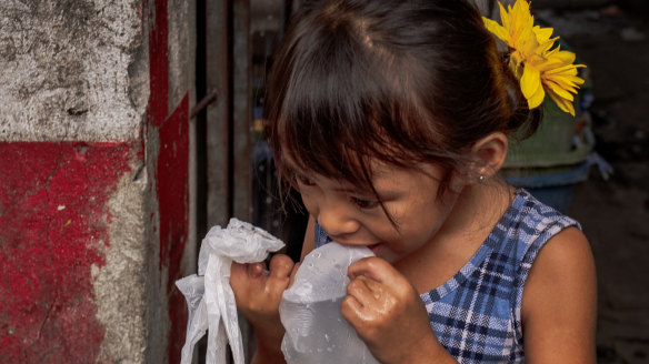 A girl drinks water from a plastic bag amid extreme heat at Tondo district in Manila, Philippines.
