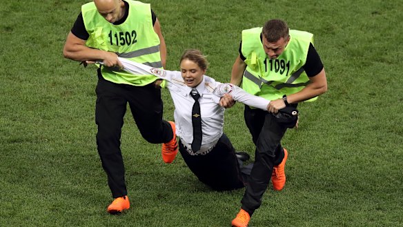 A woman is dragged from the pitch after the invasion in the second half.