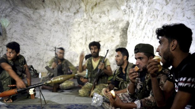 Fighters with the Free Syrian army eat in a cave where they live, on the outskirts of Idlib city, on Sunday.