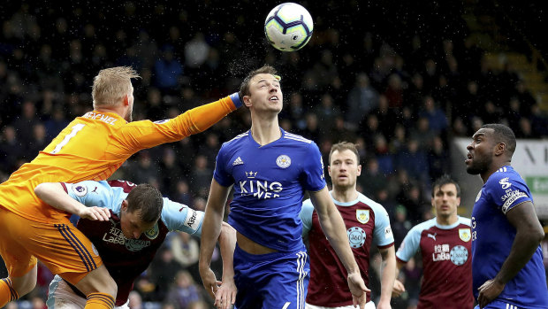 Leicester City goalkeeper Kasper Schmeichel, left, jumps over Burnley's Chris Wood to punch the ball.