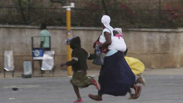 What appears to be a mother and children flee violence in Zimbabwe's capital.