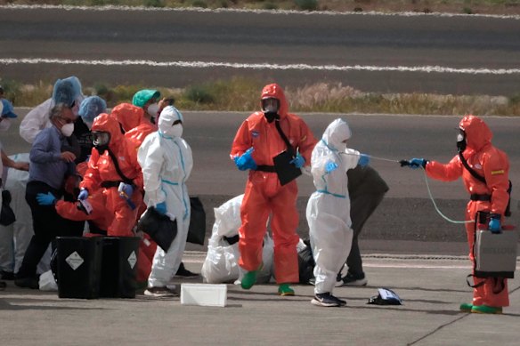 Passengers from the MV Hondius cruise ship are sprayed with disinfectant by Spanish officials.