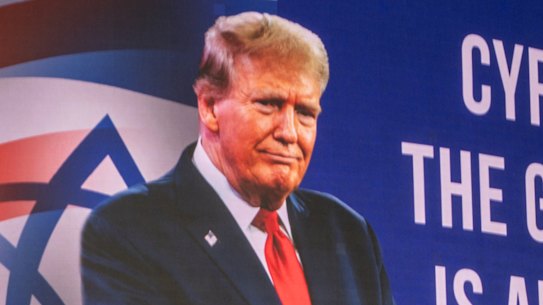 People walk underneath a billboard praising Trump.