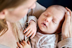 Close-up of caring mother lovingly holding her newborn baby in a close embrace (stock image)