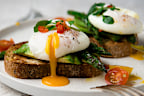 Poached eggs on toast with avocado, asparagus, tomatoes and sprout for healthy breakfast.