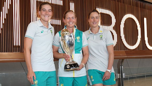 Annabel Sutherland, Meg Lanning and Ellyse Perry pose with the World Cup trophy after arriving home in Melbourne.