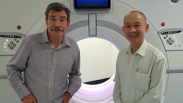 Michael Beatty (left) with Professor Kwun Fong in front of the CT scanner at Prince Charles Hospital.