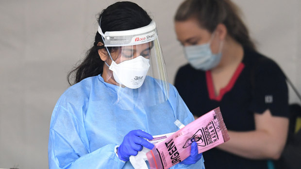 A health worker handles a COVID-19 swab at a drive through testing clinic.