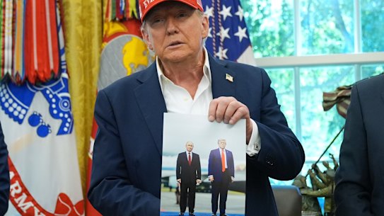 Trump displays an image of himself with Putin last week, and said the Russian leader had expressed the desire to attend the soccer World Cup in the US next year.