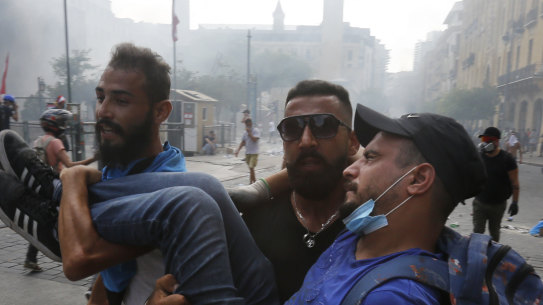 Protesters carry a wounded man during demonstrations on August 8, in Beirut, Lebanon. 