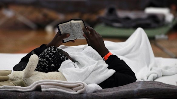 A migrant woman reads a Bible as she rests inside the Portland Exposition Building in Portland, Maine.