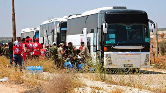 Syrian government forces and Syrian Arab Red Crescent oversee the evacuation by buses of opposition fighters and their families from the southern province of Daraa, Syria, to Idlib in July.