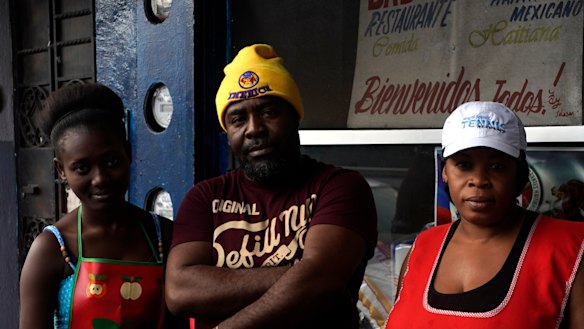 Haitian immigrant Wilthene Pierre poses for a photo with two of his cooks Emily, left, and Violette Novembre, in front of the Kriskapab Baborijinal Haitian restaurant in Tijuana.