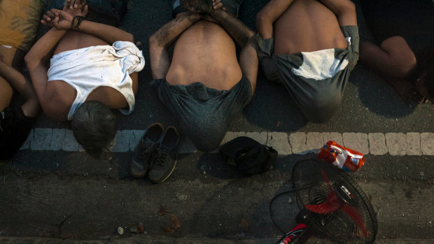 People lie on the ground after being detained for allegedly looting a supermarket during a continued power outage in Santa Cruz del Este, Caracas, Venezuela.