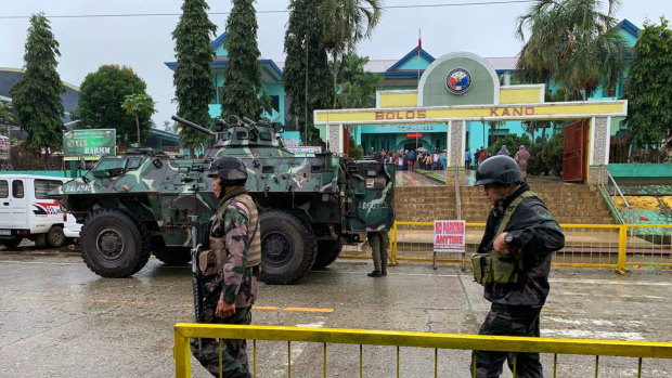 Soldiers walk near an armoured personnel carrier parked outside the Saguiaran city hall in Lanao del Sur province, southern Philippines, during the  referendum on a new autonomous region.