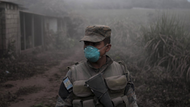 A soldier stands guard at a search and rescue site near the Volcan de Fuego, or "Volcano of Fire," in Escuintla, Guatemala.