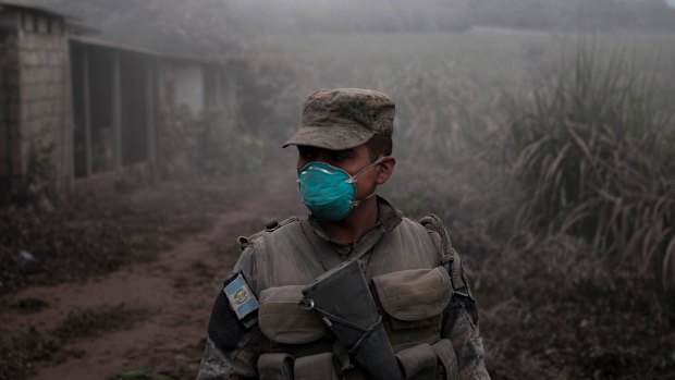 A soldier stands guard at a search and rescue site near the Volcan de Fuego, or "Volcano of Fire," in Escuintla, Guatemala.