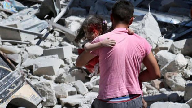 A Syrian man carries an injured girl after an air strike hit an open-air market in Ariha, Idlib province, in July, killing several people.