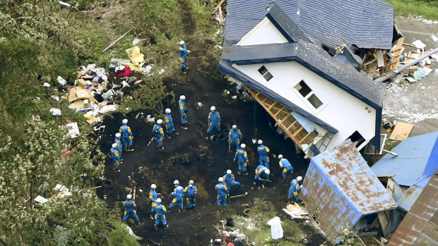Police search for missing people around houses destroyed by an earthquake in Atsuma town, Hokkaido, southern Japan, on Friday, 