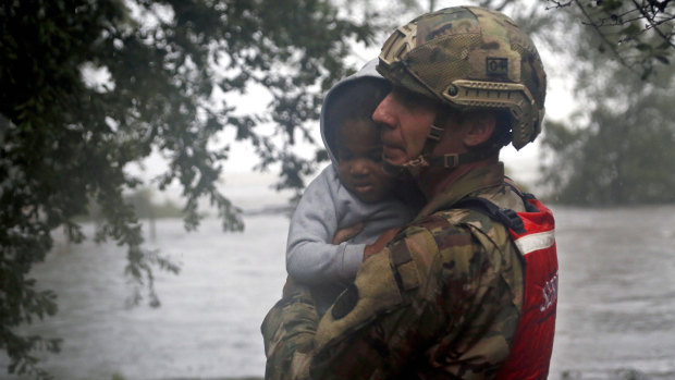 Rescue team member Sergeant Nick Muhar, from the North Carolina National Guard 1/120th battalion, evacuates a young child.
