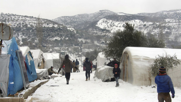 Syrians walking outside their tents at a displaced people camp near Turkish border, in Idlib province, Syria. 