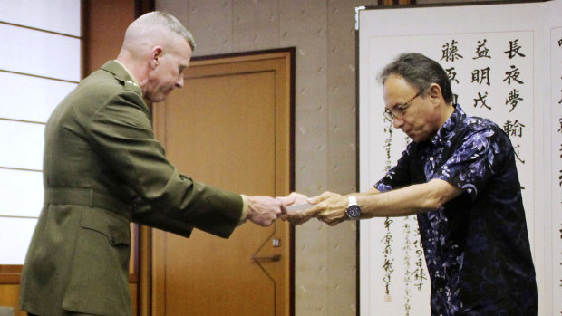 Okinawa Governor Denny Tamaki, right, hands out a letter of protest to Lieutenant General Eric Smith, US Marines commander in Japan, on Monday.