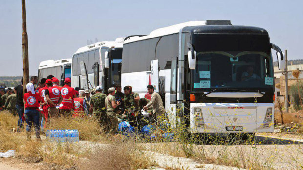 Syrian government forces and Syrian Arab Red Crescent oversee the evacuation by buses of opposition fighters and their families from the southern province of Daraa, Syria, to Idlib in July.