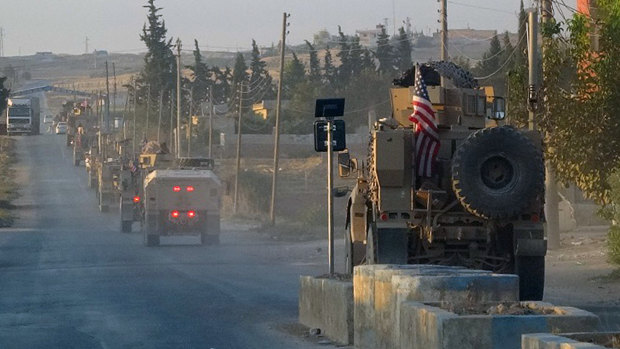 US military vehicles travel down a main road in north-east Syria.