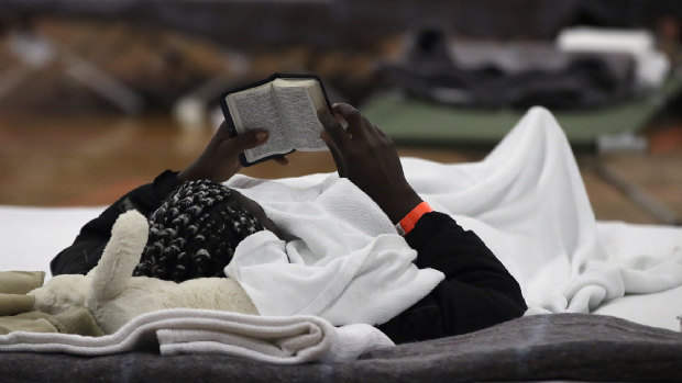 A migrant woman reads a Bible as she rests inside the Portland Exposition Building in Portland, Maine.