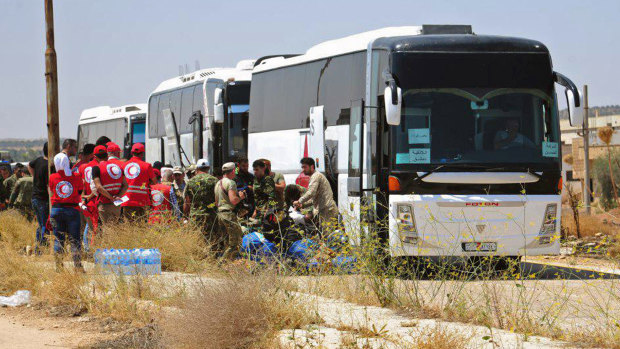 Syrian government forces and Syrian Arab Red Crescent oversee the evacuation by buses of opposition fighters and their families from the southern province of Daraa, Syria, to Idlib in July.