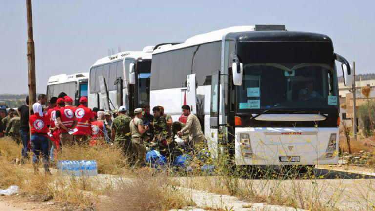 Syrian government forces and Syrian Arab Red Crescent oversee the evacuation by buses of opposition fighters and their families from the southern province of Daraa, Syria, to Idlib in July.