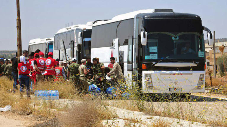 Syrian government forces and Syrian Arab Red Crescent oversee the evacuation by buses of opposition fighters and their families from the southern province of Daraa, Syria, to Idlib in July.