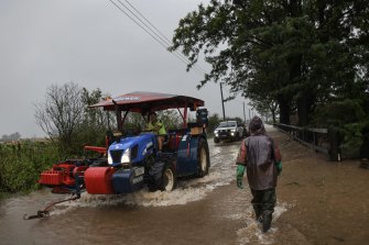 Farmers evacuate equipment in Pitt Town as heavy rains associated with an east coast low impact the Sydney basin.