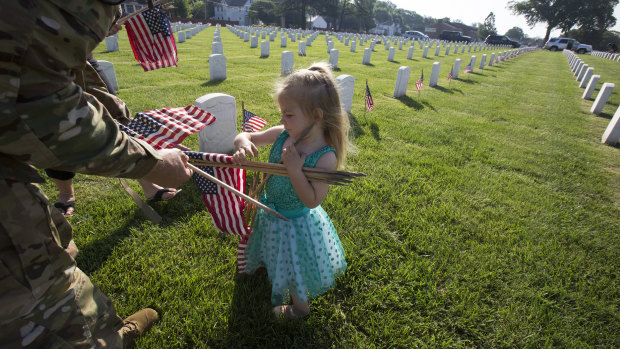 On Memorial Day weekend in the US, Samara Reiseweber 2, helps her father  Lieutenant-Colonel Andrew Reisenweber place flags at graves in Hampton, Virginia. 
