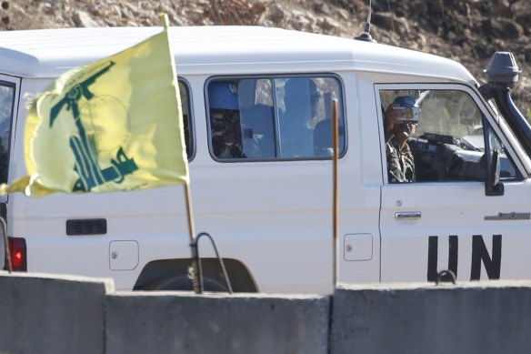 United Nations personnel drive past a Hezbollah flag on a concrete barrier in southern Lebanon on the border with Israel on Wednesday. The US wants a reduction of UN peacekeeping forces in Lebanon.