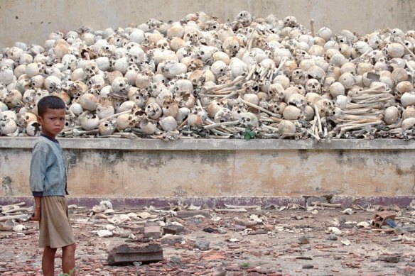 A Cambodian boy stands in front of  human skulls discovered south of Phnom Penh in 1995. The mass grave contains the remains of about 2000 victims of the Khmer Rouge.