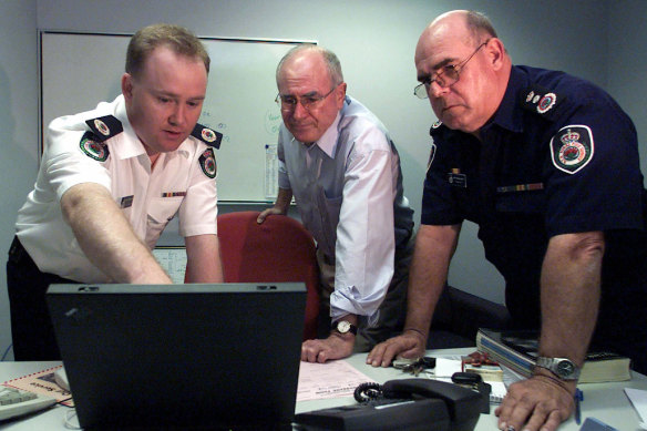 Then prime minister John Howard is briefed by Shane Fitzsimmons (left) and Phil Koperberg (right) of the RFS in 2001 about a fire that devastated Warragamba in the Blue Mountains.