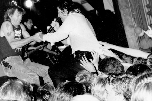 “Am I ever gonna see your face again?” A roadie rescues Angels’ singer Doc Neeson from his audience in 1986.