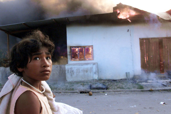 September 1999: A girl walks by a burning house in Dili, East Timor, two days before the arrival of Australian peacekeeping troops.