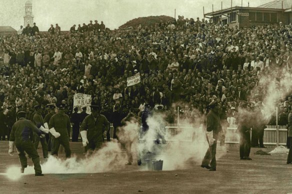 Police pick up missiles and smoke bombs hurled by demonstrators from the hill at SCG during the NSW- Springboks rugby match to day. July 10, 1971.