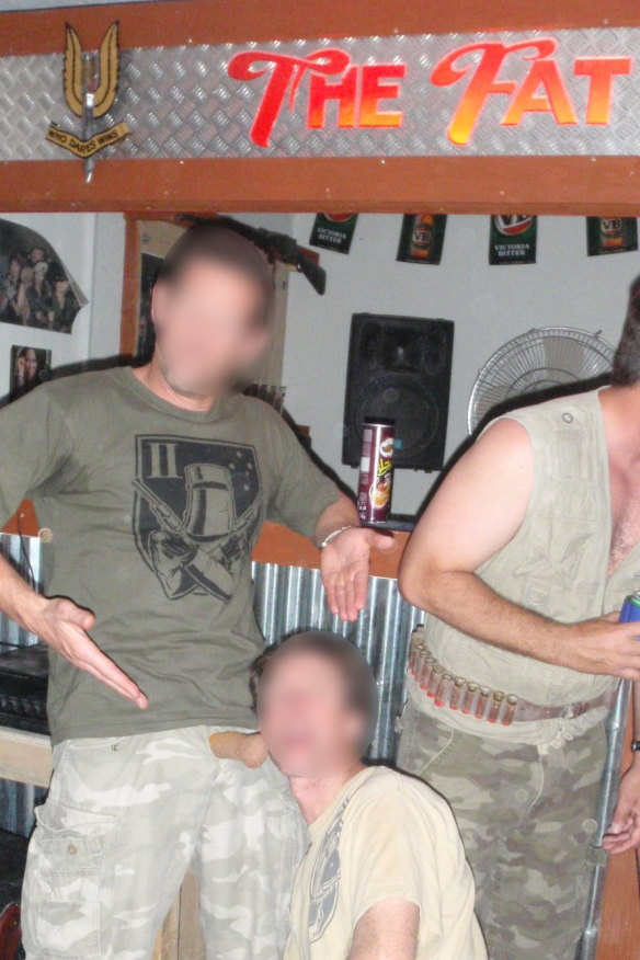 A senior SAS officer, left, and a non-commissioned officer, kneeling, pretend to engage in a sex act using an object designed to look like a penis at a party in the makeshift Fat Ladies Arms bar.