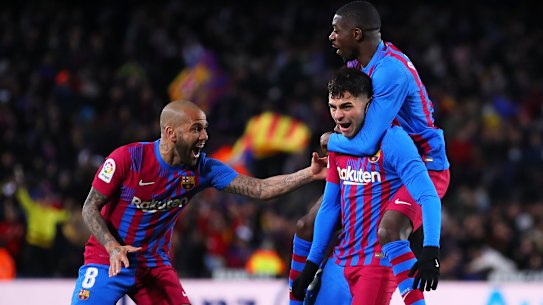 Pedri celebrates a goal for FC Barcelona with teammates Dani Alves (left) and Ousmane Dembele.