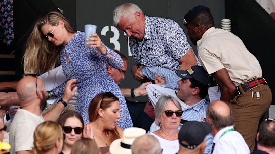 Security staff and spectators remove the 22-year-old from the stands during the men’s final at Wimbledon.